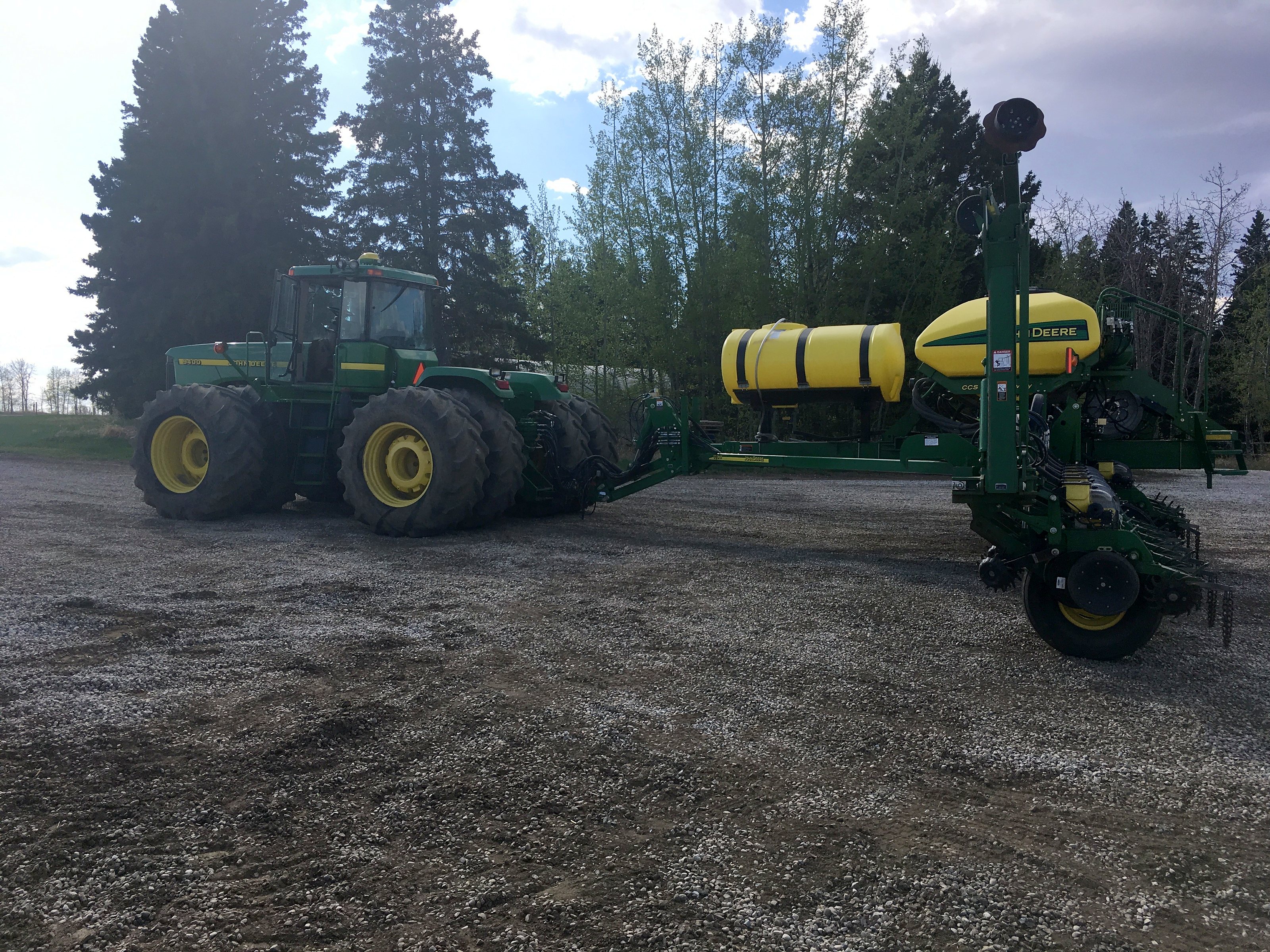 The group's John Deere four-wheel-drive tractor and air seeder at the treeline in spring