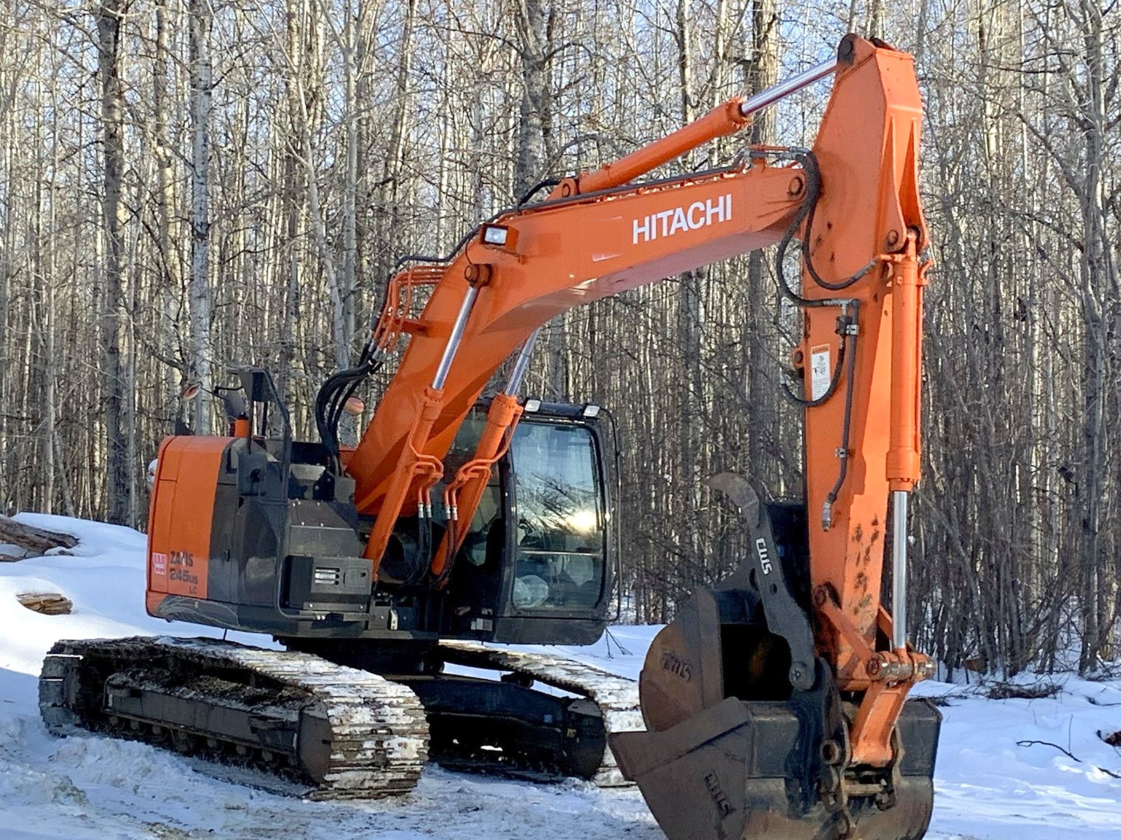 The group's Hitachi ZX245 excavator at the treeline