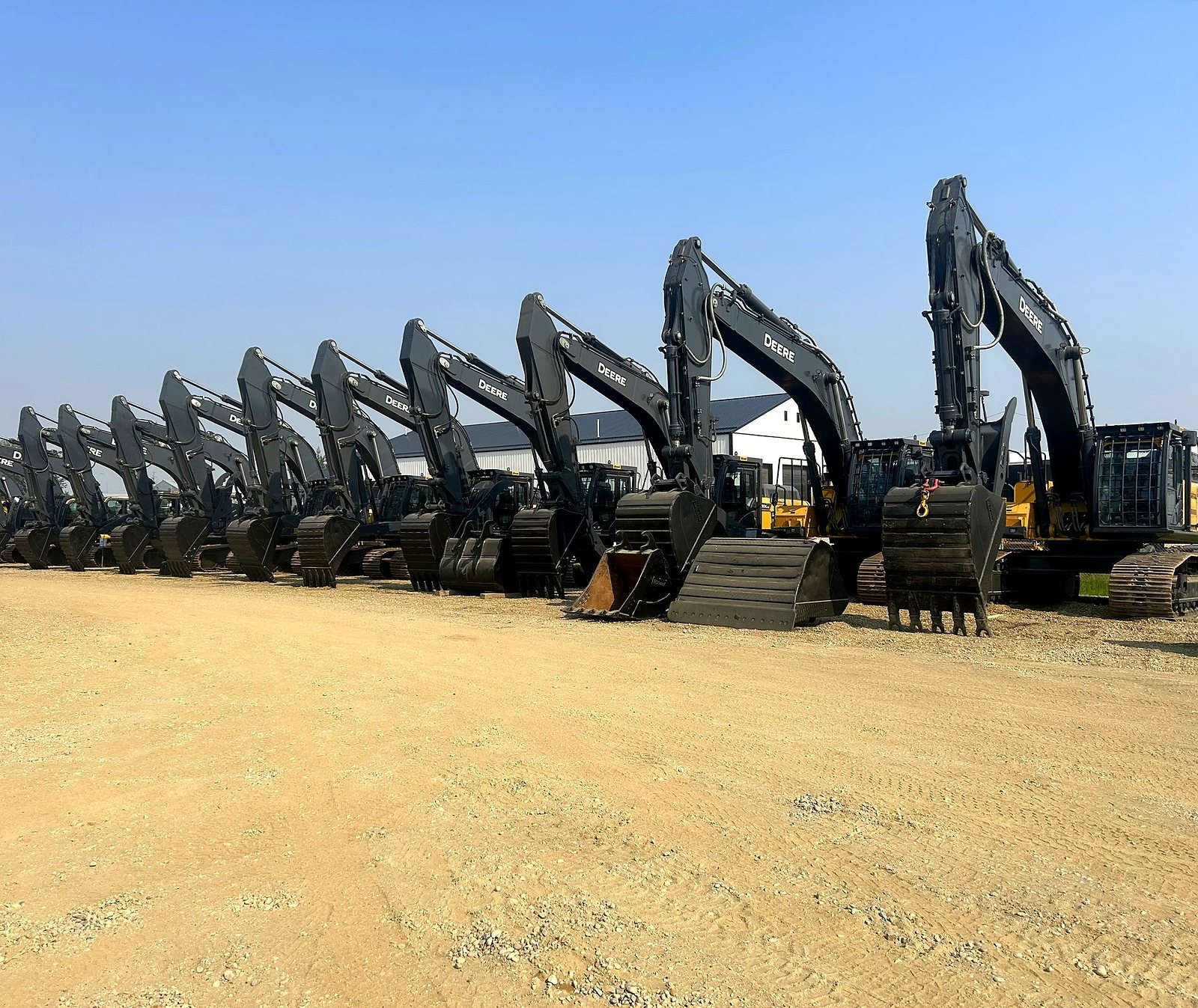 A row of John Deere excavators in the group's yard