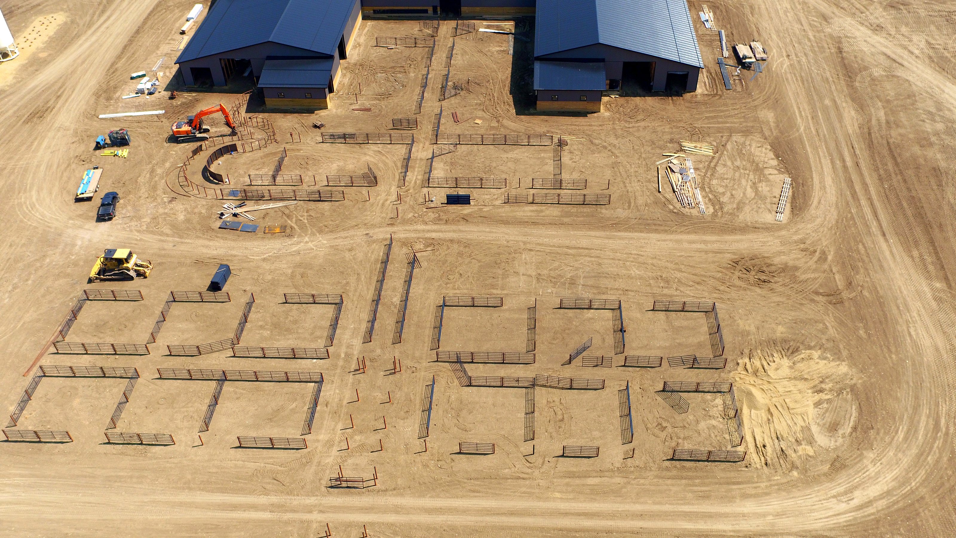 Building the feedlot pens, an excavator and a loader at work, from Overwatch
