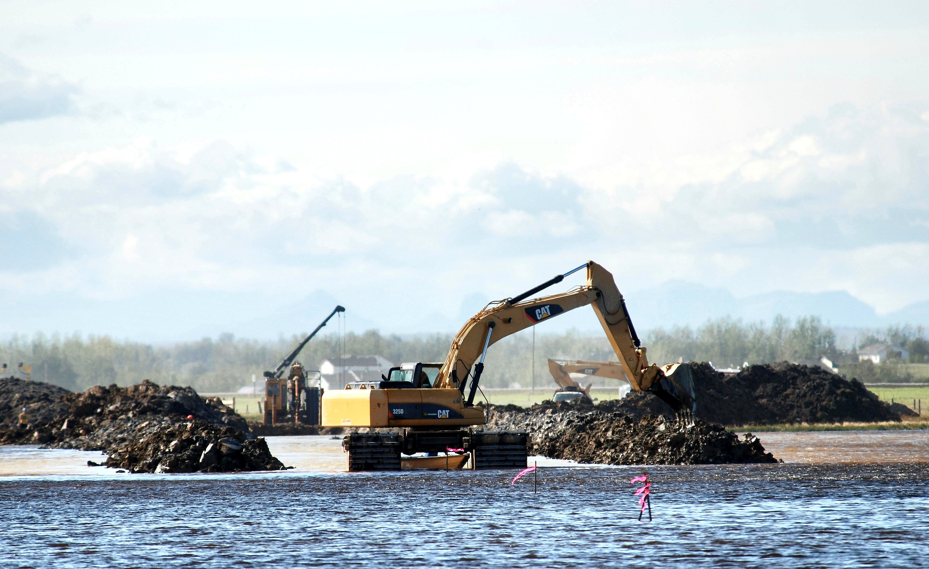 A Cat 325D on pontoons in open water at Weed Lake, Alberta